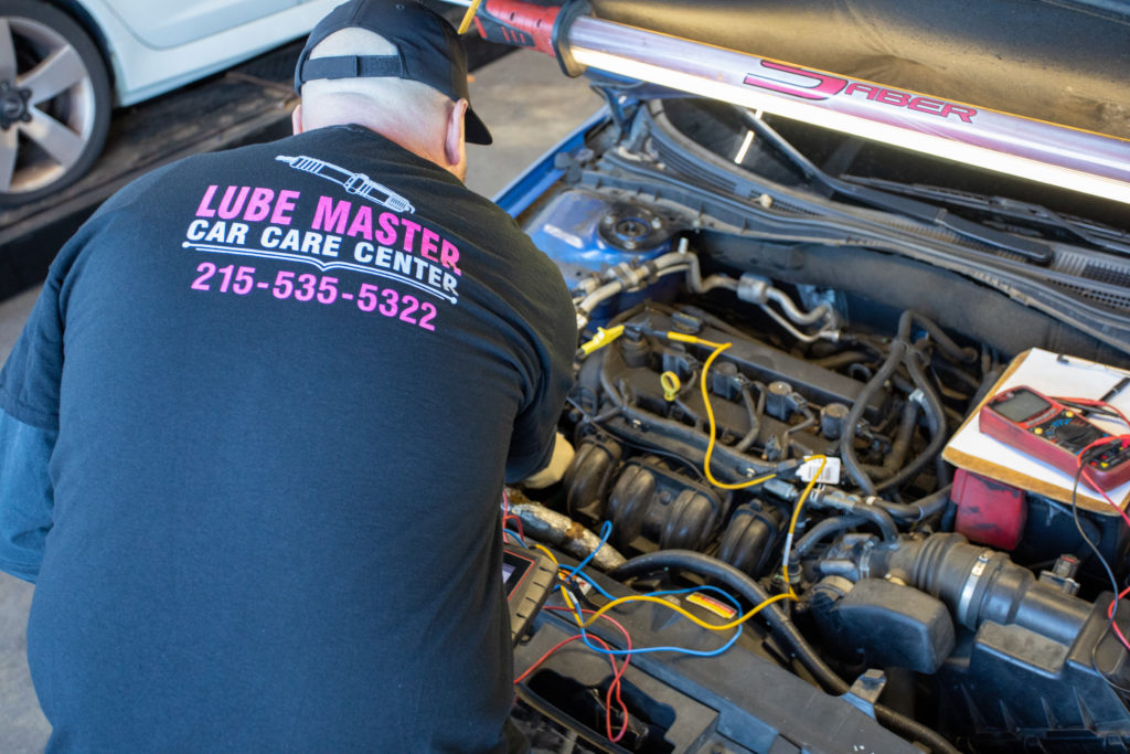 A Lube Master employee inspecting a vehicle’s engine.