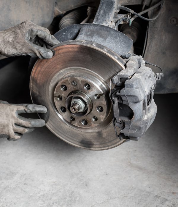 A mechanic replaces a car’s rotor in a garage.